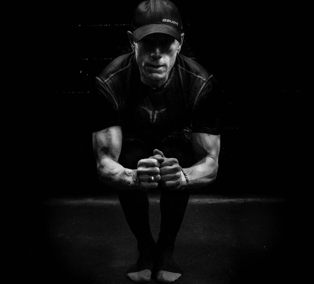 Rick Scott crouched in a Bauer cap and hockey gloves, black and white